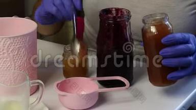 女人把果酱放进量勺里。 准备棉花糖。 桌子旁边还有其他原料和工具